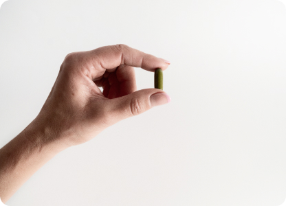 A capsule being held between thumb and forefinger