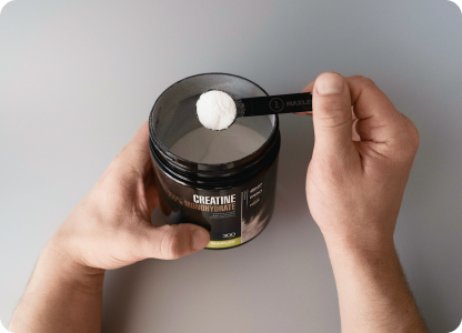A scoop of Creatine 100% Monohydrate being taken out of a can