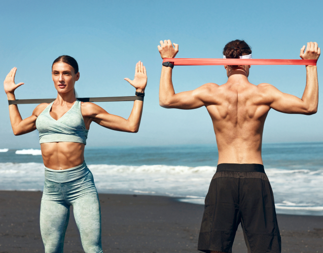 A woman and a man doing exercises on the ocean shore
