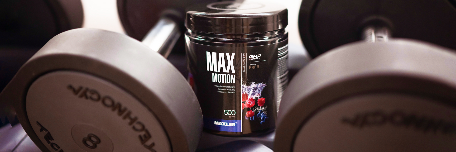 A can of Max Motion and a pair of dumbbells