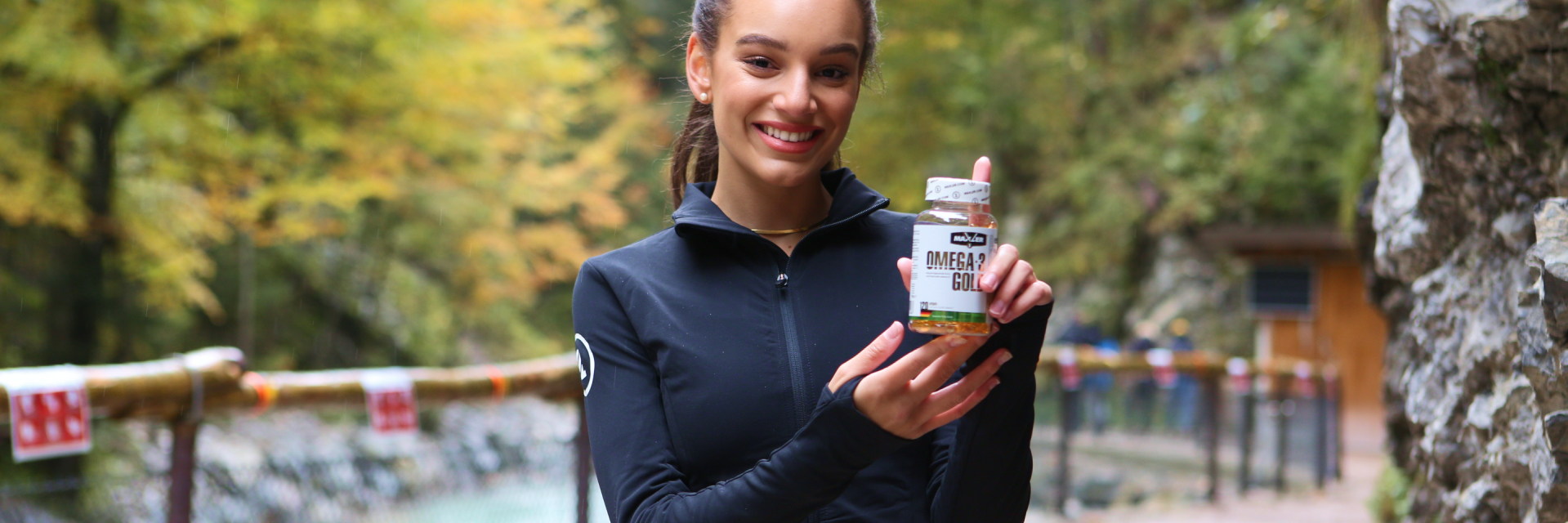 A smiling woman with a Omega-3 Gold EU bottle