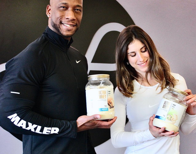 A man and a woman each holding a bottle of Ultra Whey