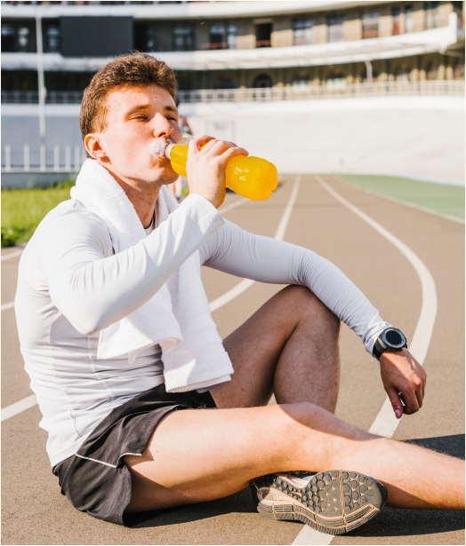 A man sititng on race track drinking from a shaker